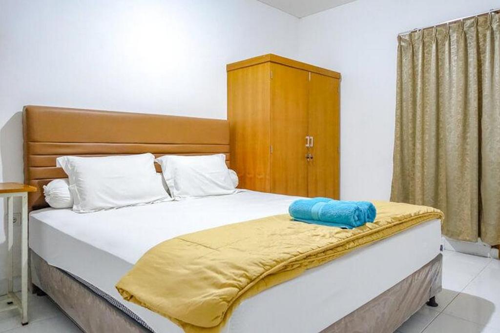 a bedroom with a bed with a yellow blanket on it at Sofia Residence Syariah Mitra RedDoorz in Malang