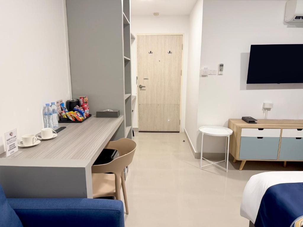 A room workspace with a built-in desk, chair, drinks, television and storage furniture.