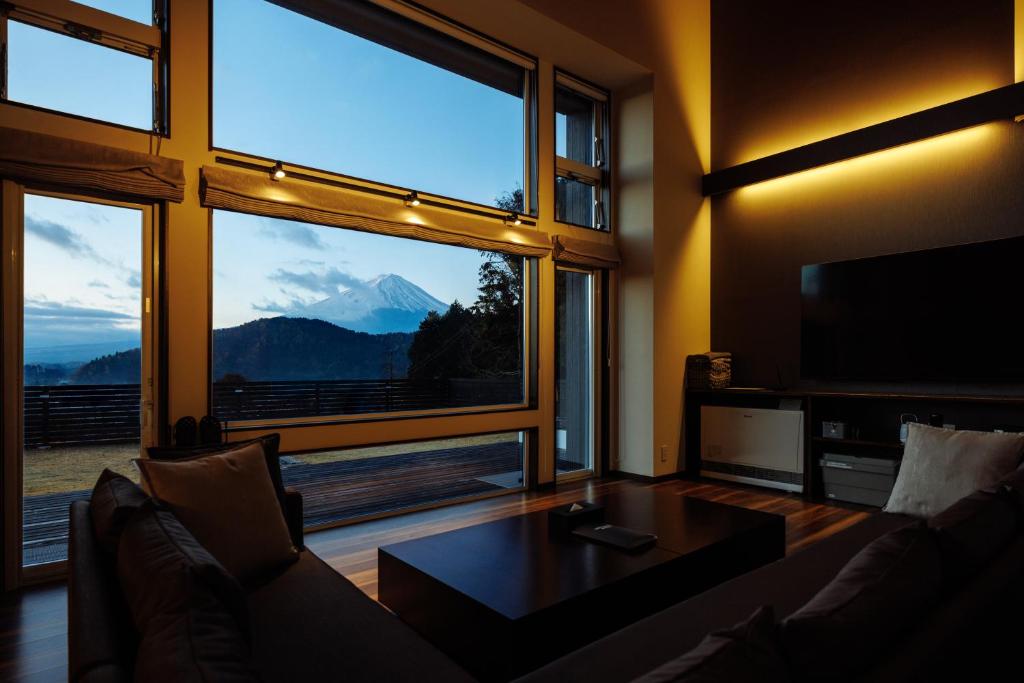 un soggiorno con un divano e una grande finestra di Private villa FujiNagi a Oishi