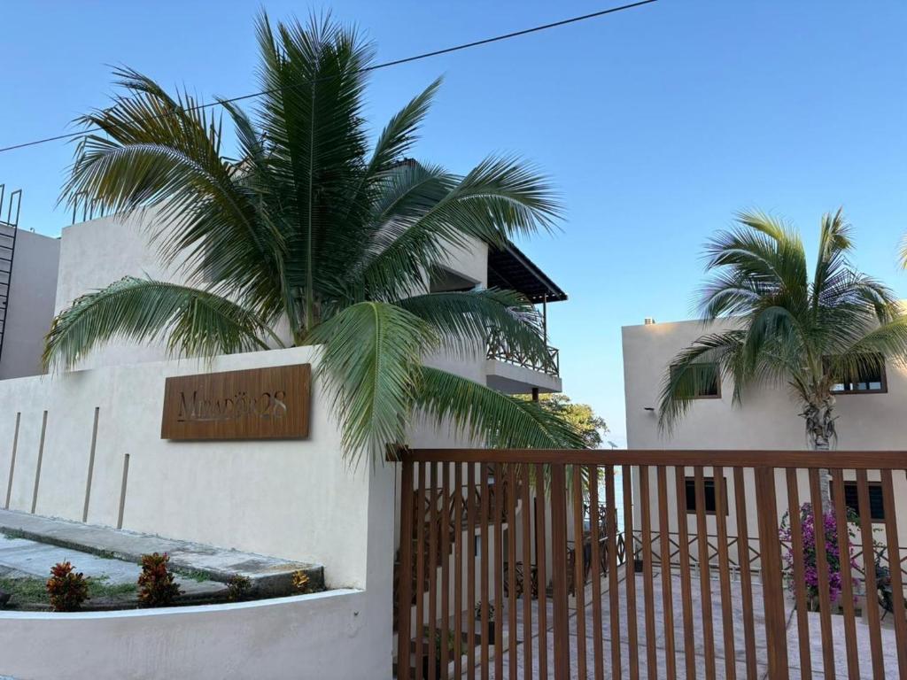 un edificio bianco con una recinzione e una palma di Mirador 28 a Platanitos