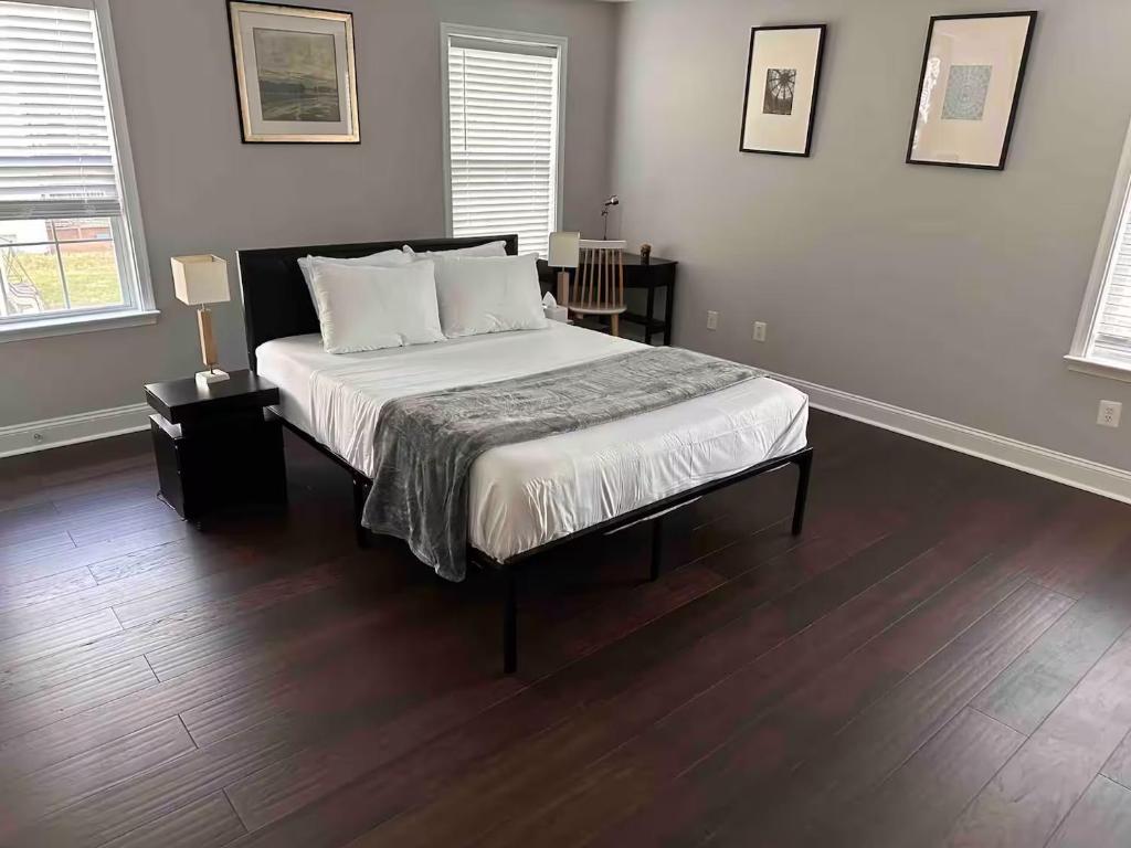a bedroom with a bed with white sheets and wood floors at 25 Lux King Suite 1 - Private Bath, Nonsmoking in Arlington