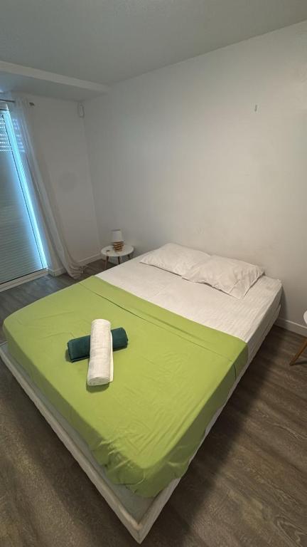a bed with a green blanket and a towel on it at Le Swing in Saint-François