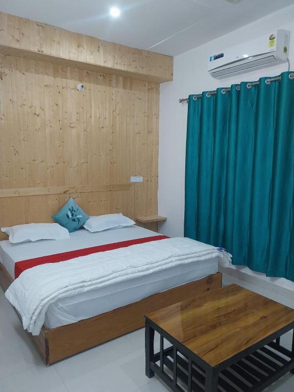 a bedroom with a large bed with a blue curtain at Hotel Dharam Ganga in Uttarkāshi