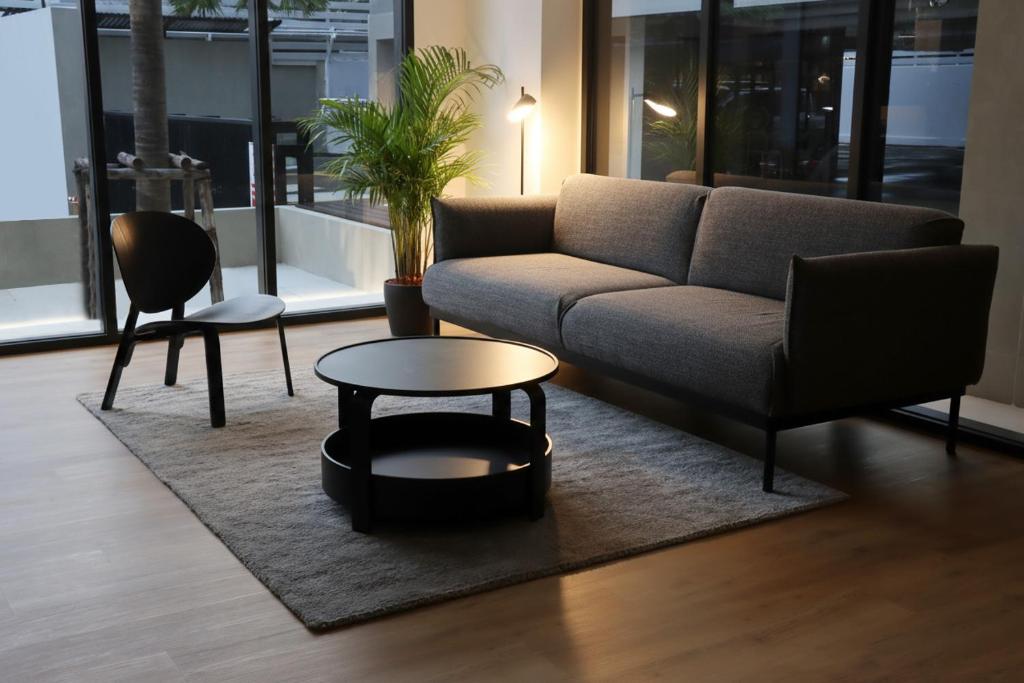 A contemporary lounge with a sofa, armchair and round coffee table beside large windows.
