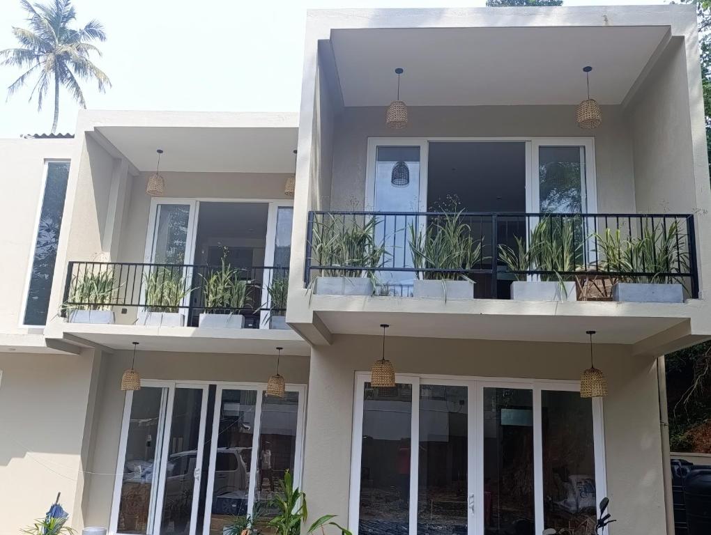 een wit huis met potplanten op de balkons bij LUSSO Mirissa in Mirissa