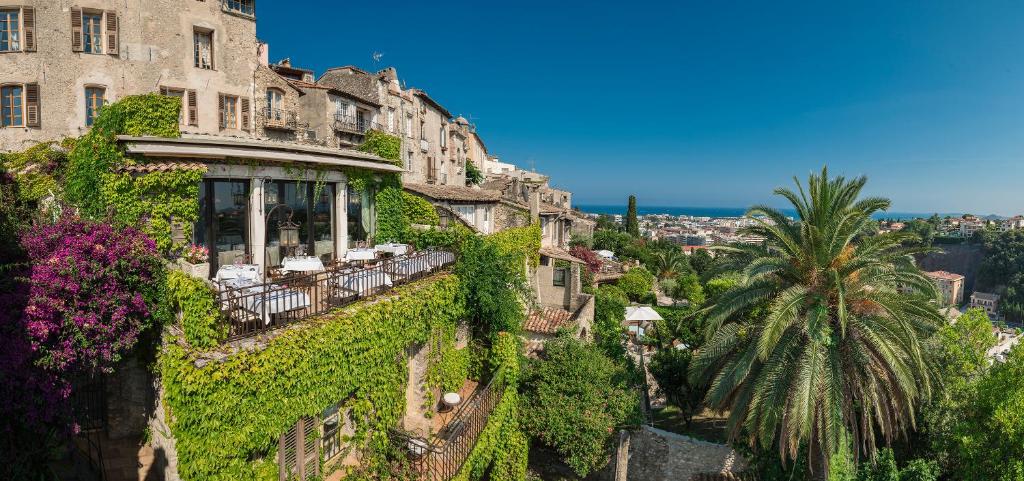 a building covered in ivy with a palm tree at Château Le Cagnard in Cagnes-sur-Mer