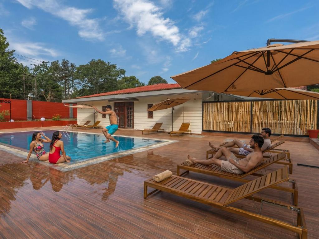 a group of people laying on chaises by a swimming pool at The Hosteller Bam Coorg in Madikeri