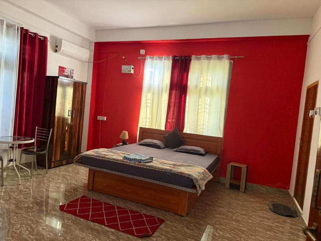 a bedroom with a bed with red walls and a table at Jorhat HideAway in Jorhat