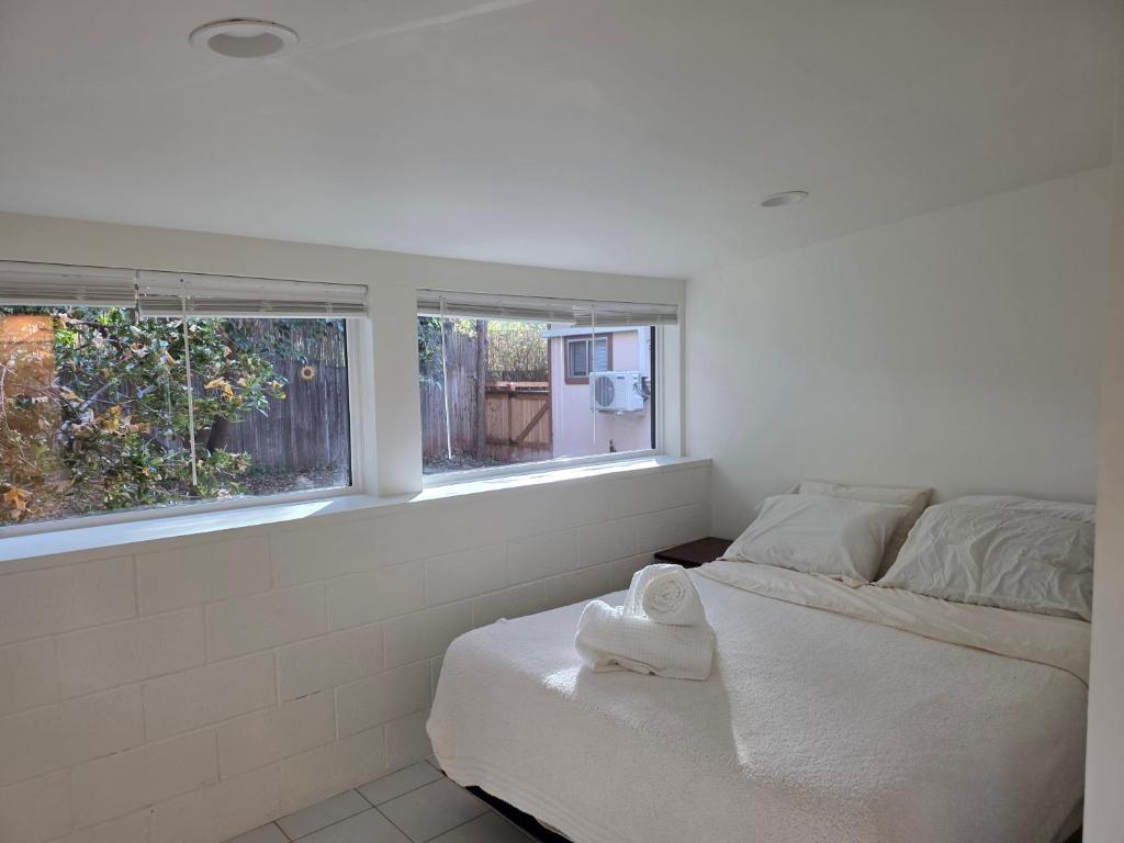 a white bedroom with a bed and two windows at West Sedona Garden Suite in Sedona