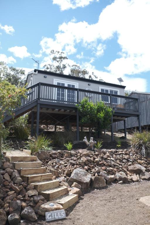 a house with a deck and a rocky yard at Gills in Murdunna