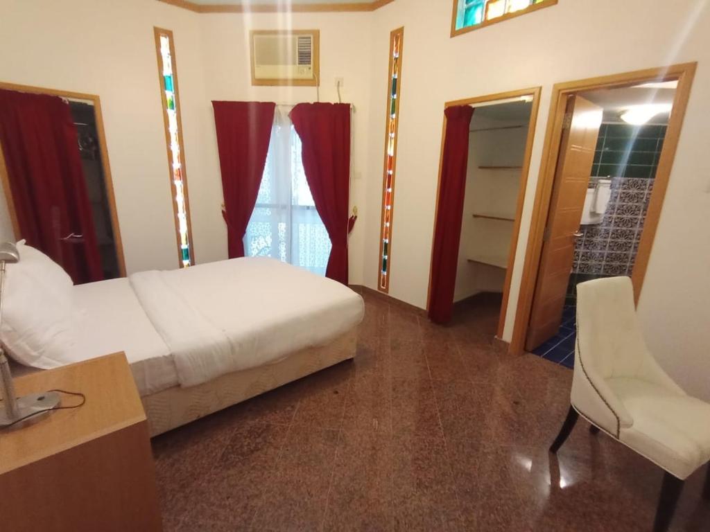 een slaapkamer met een bed, een bureau en een stoel bij Qurum Heights Hotel in Muscat