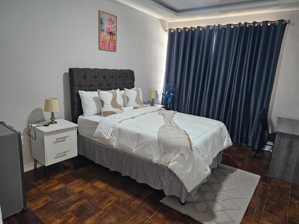 a bedroom with a large bed with blue curtains at Phozi Inn in Eshowe