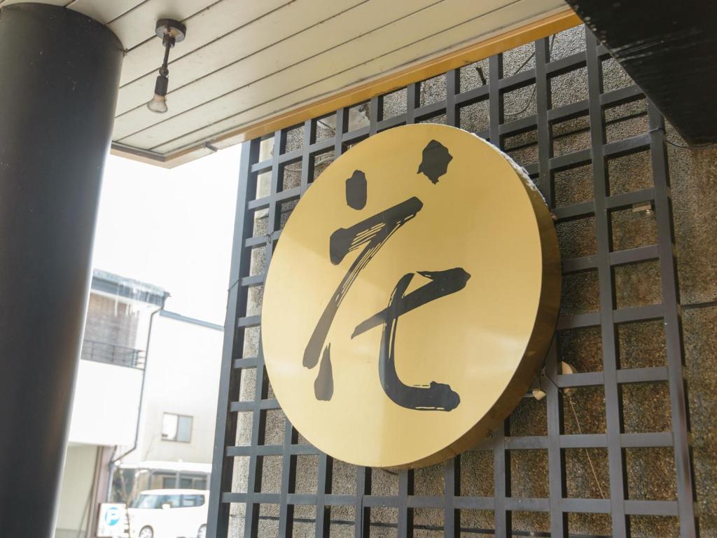 a yellow sign on a fence with a man and a stick at Hotel Hana in Takayama