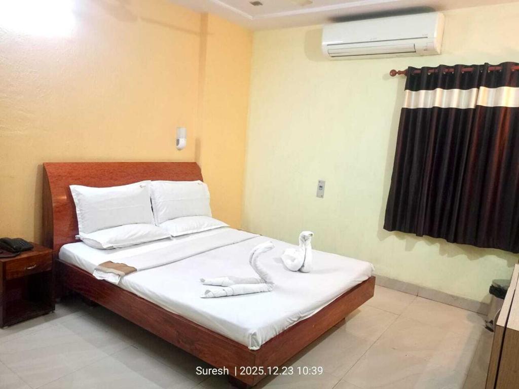 a bedroom with a bed with white sheets and swans on it at Challa Residency in Rājahmundry