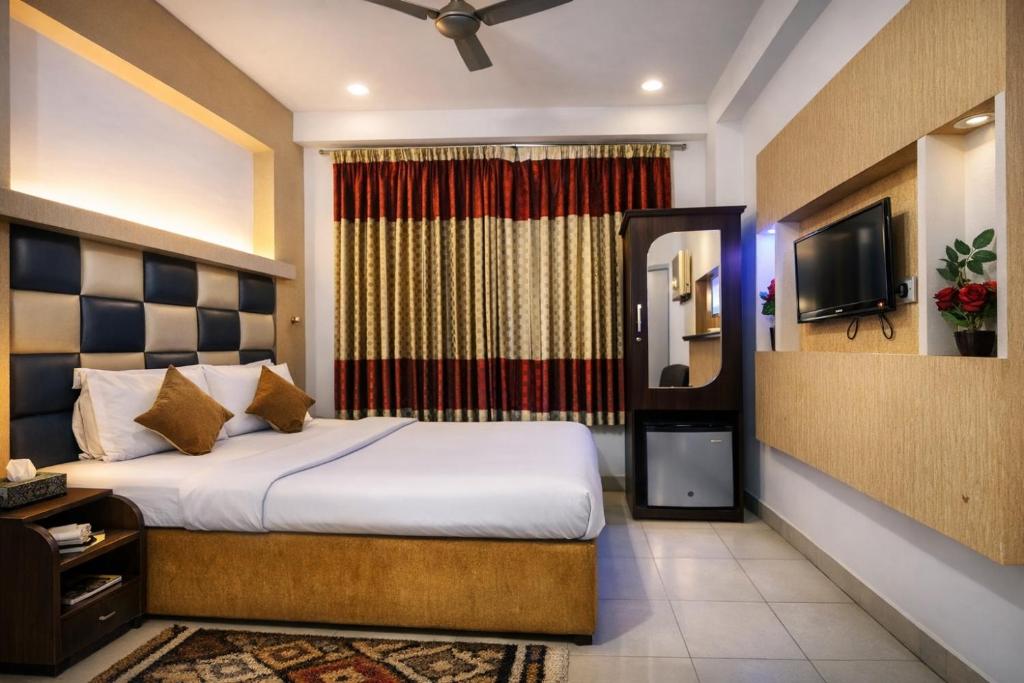 een hotelkamer met een bed en een televisie bij Baral White Rose Hotel in Dhaka