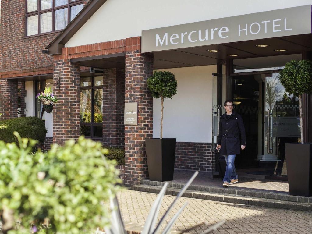 een vrouw die uit een Mercure hotel loopt bij Mercure Dartford Brands Hatch Hotel & Spa in Ash