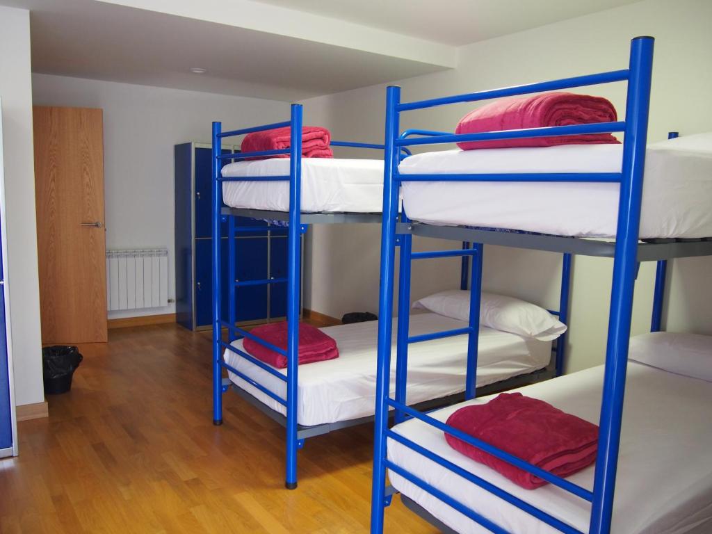 Habitación con literas azules y almohadas rojas. en Albergue Segunda Etapa, en Zubiri
