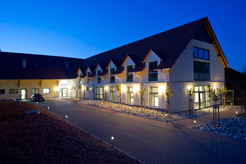 ein großes weißes Gebäude mit einem Parkplatz in der Nacht in der Unterkunft Apartments Golfpark Schlossgut Sickendorf in Lauterbach