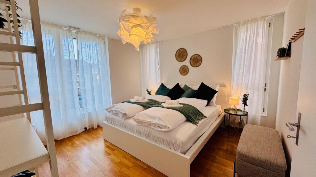 a bedroom with a large white bed with a chandelier at Mountainview Apartment - Central - Family - Hiking - Lake and Mountains in Schwyz