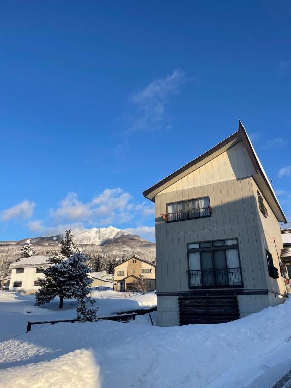 a house with snow on the ground in front of it at Sugi Mountain House in Myoko