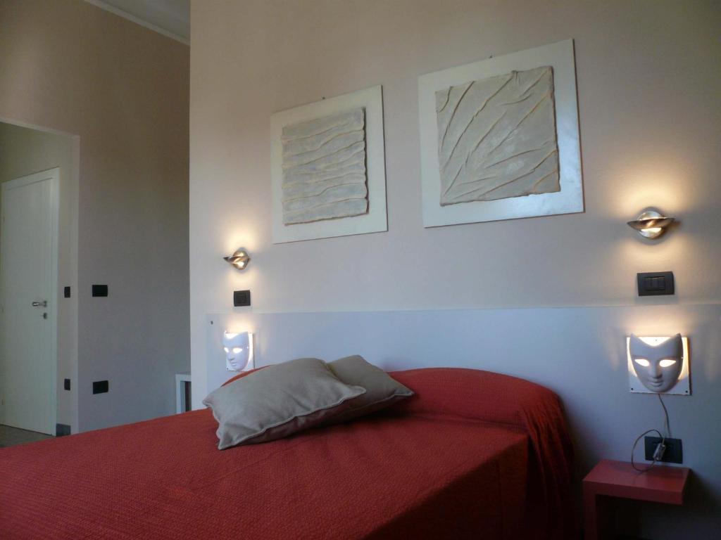 een slaapkamer met een rood bed met twee foto's aan de muur bij Lucca In Villa Elisa & Gentucca in Lucca
