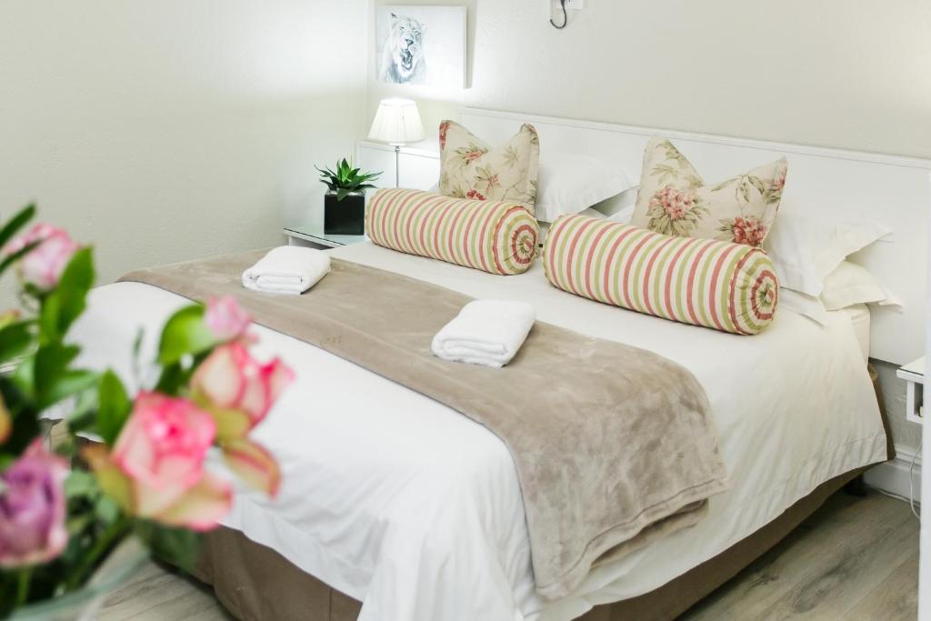 a bedroom with a white bed with pillows and flowers at Wagon Wheel Country Lodge in Beaufort West