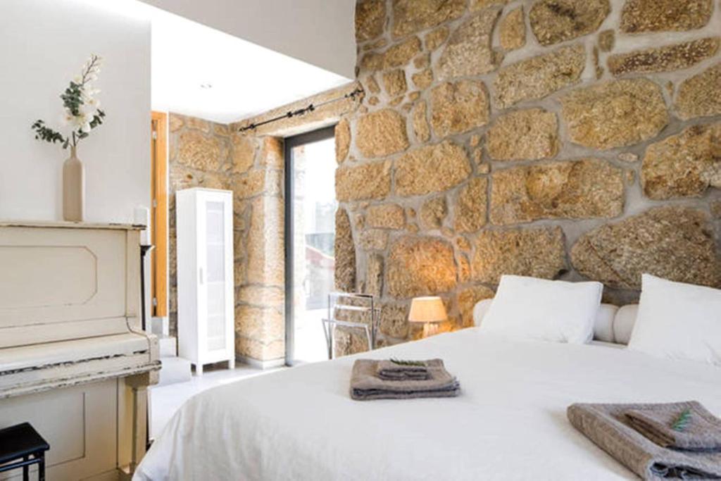 a stone walled bedroom with a bed and a fireplace at Villa Lugar do Pego in Tondela