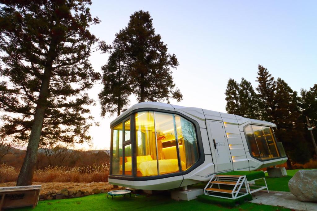 a tiny house sitting on top of a field at space-vessel基地 in Yufu