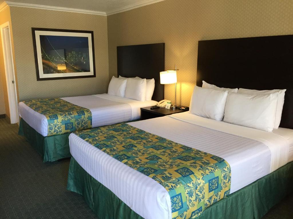 a hotel room with two beds and a lamp at Regency Inn at San Francisco Airport in San Bruno
