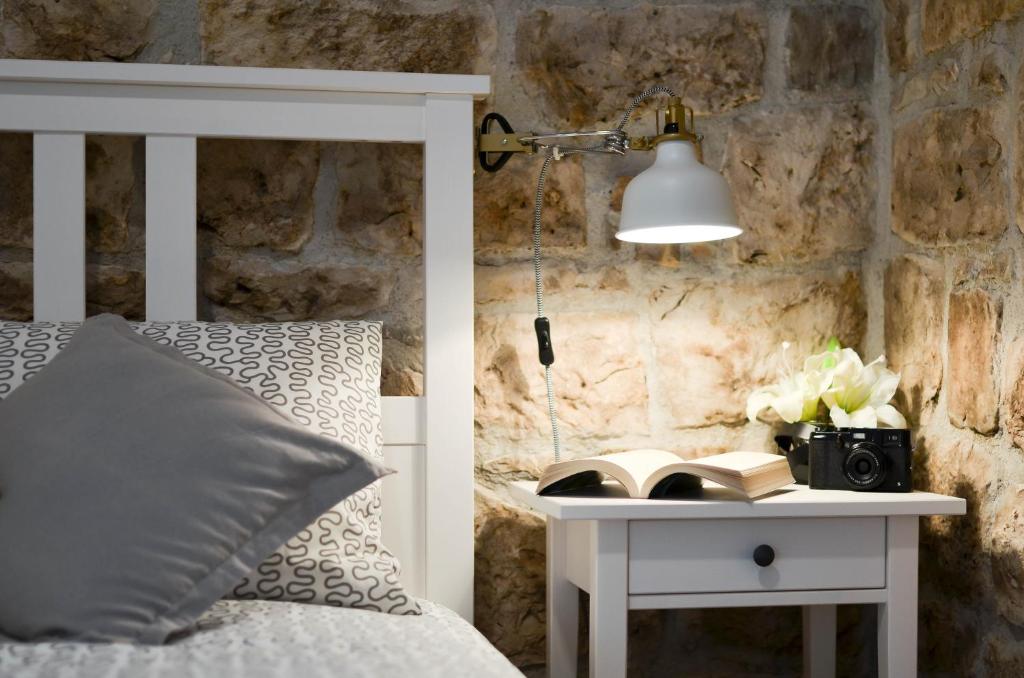 un lit avec une lampe et une table avec un livre dans l'établissement Apartment Fabijanko OldTown, à Trogir