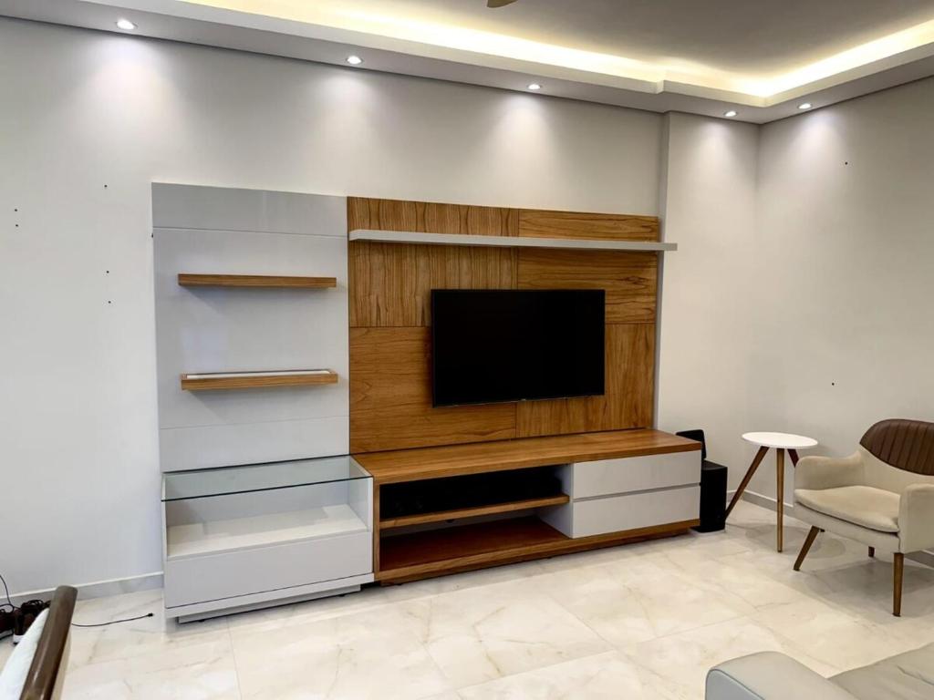 un salon avec une télévision sur un mur dans l'établissement Apartmento com 3 dorm no Canto do Forte, à Praia Grande
