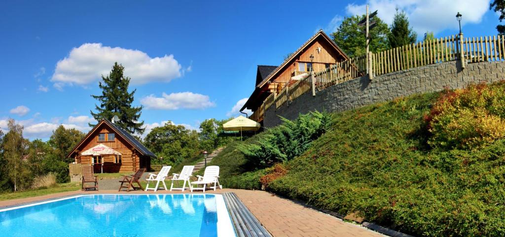 Bystrá nad Jizerou的住宿－比斯特拉大農場招待所，一个带椅子的游泳池和一个背景房子