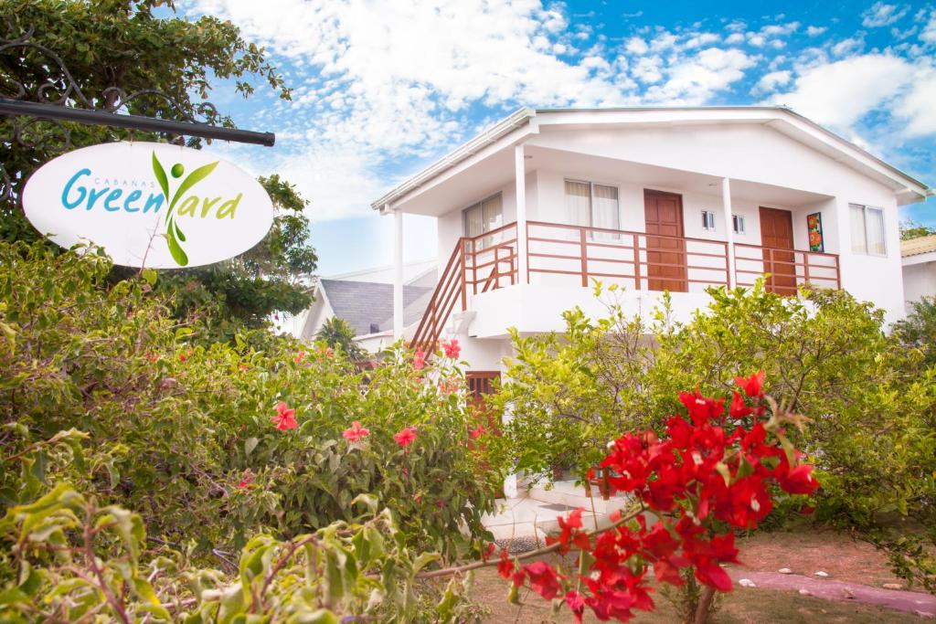 een wit huis met rode bloemen ervoor bij Cabañas Green Yard in San Andrés