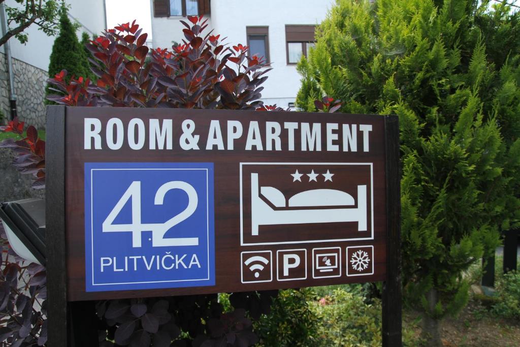 ein Schild für ein Zimmer und ein Apartment in einem Garten in der Unterkunft Room & Apartment Plitvička 42 in Slunj