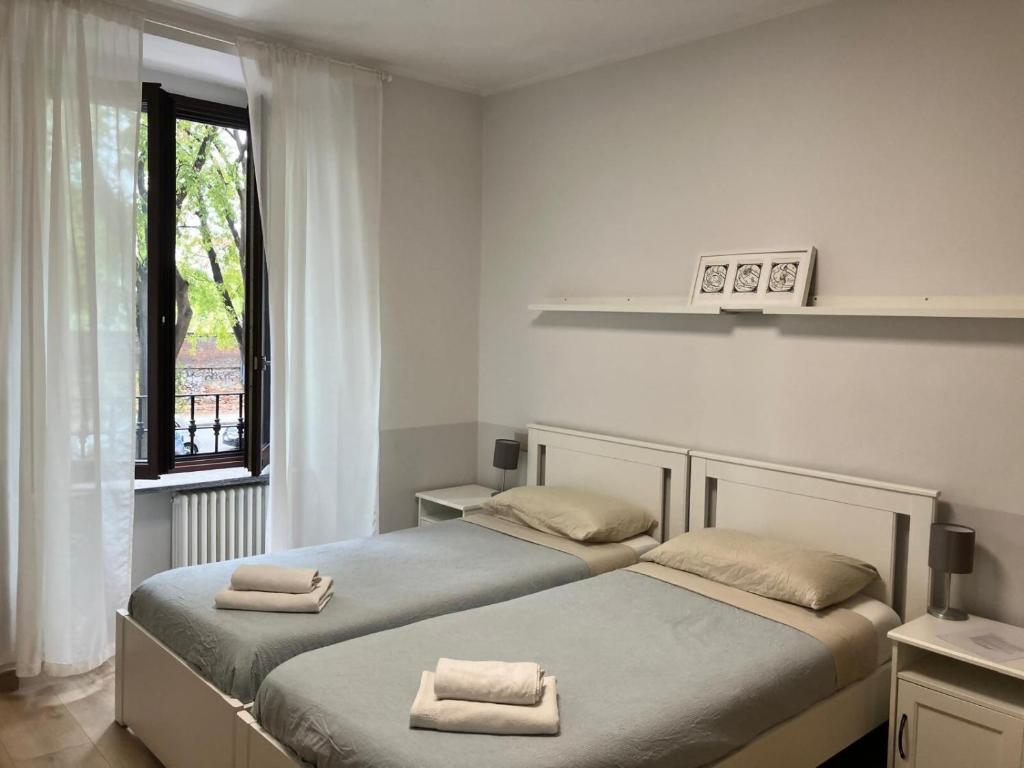 twee eenpersoonsbedden in een kamer met een raam bij Grattacielo Rooms in Turijn