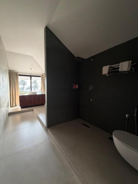 a bathroom with a white sink and a black wall at Shoonya - A Boutique Stay in Varkala