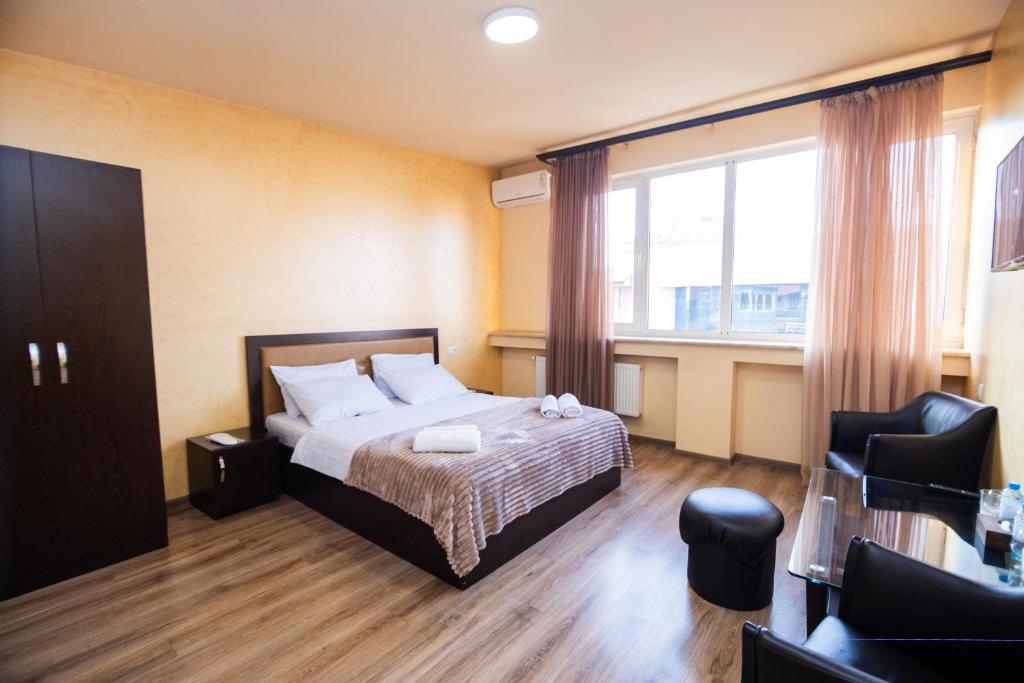 a bedroom with a bed and a chair and a window at MBM Hotel in Yerevan