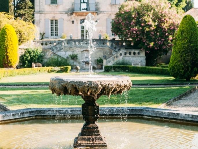 een fontein in het midden van een tuin met een gebouw bij B&B Château Légier in Fontvieille