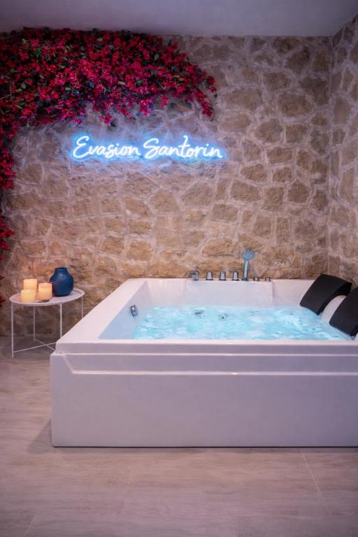 a bath tub with a sign on a wall with flowers at Évasion Santorin - Jacuzzi & Relax in Le Havre