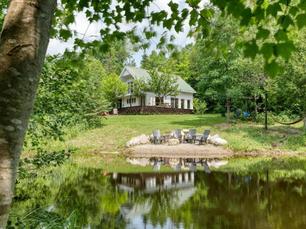 a house sitting next to a body of water at Spa et Waterfront - Cachette du Petit Lac in Chertsey