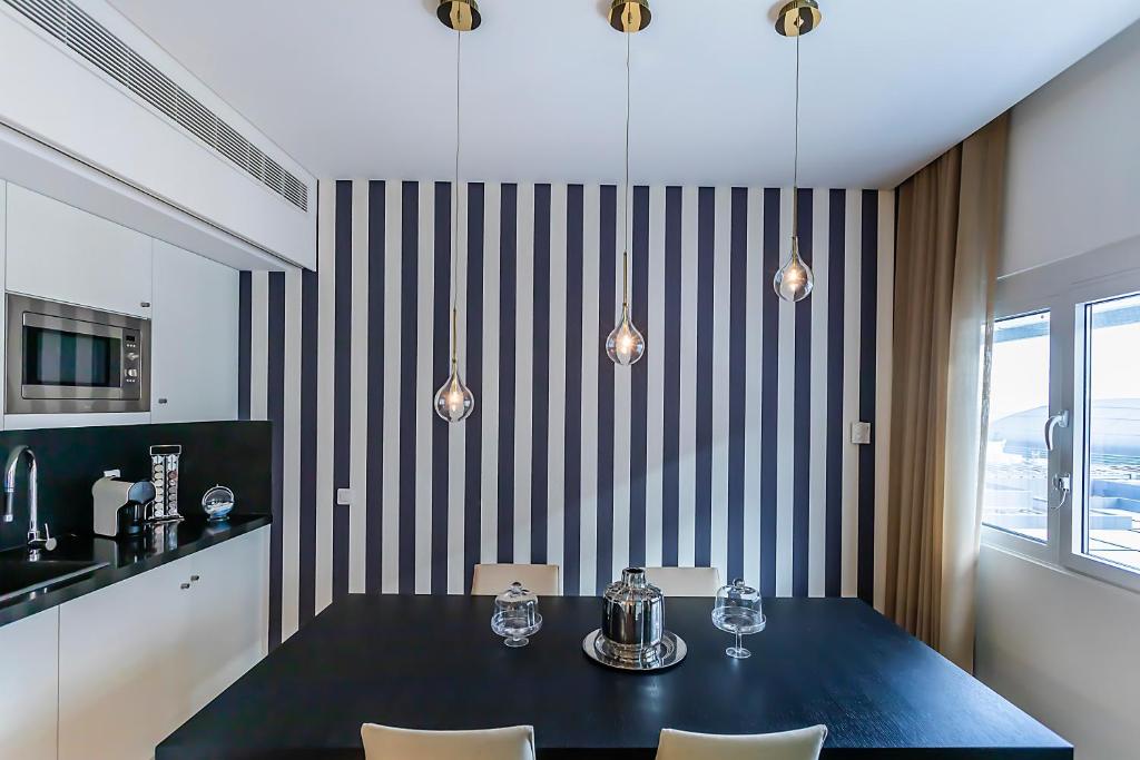 A dining area pairs a black table with pendant lights beside a compact kitchenette.