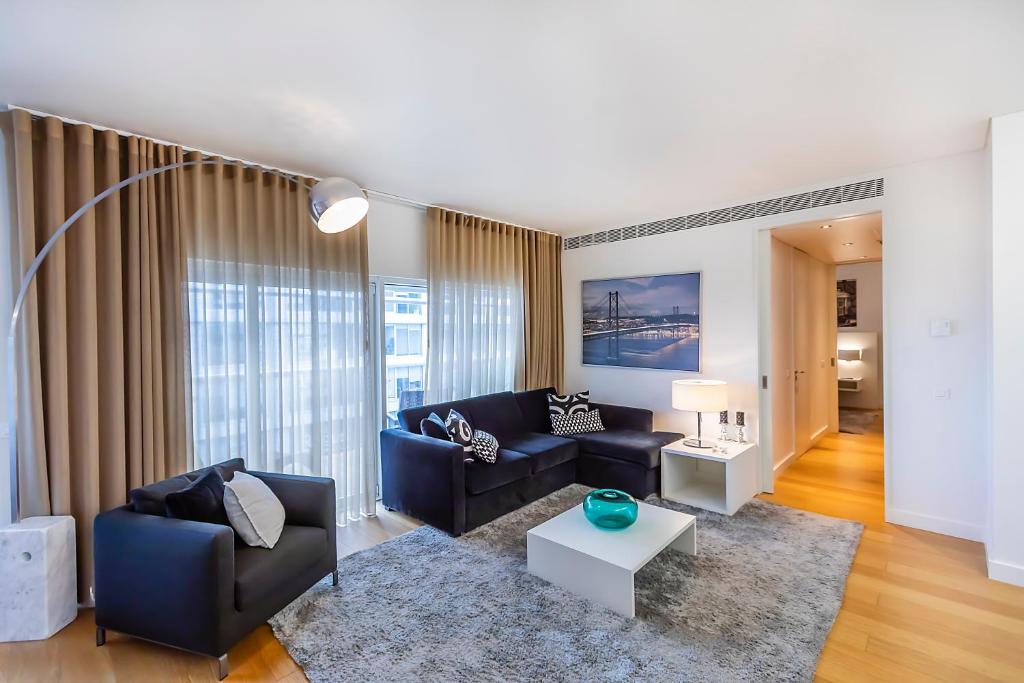 A furnished lounge opens toward curtained windows and a connecting doorway.