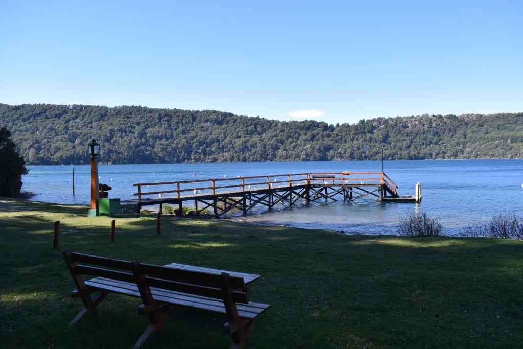a bench sitting on the grass next to a dock at Cabaña con costa de lago in San Carlos de Bariloche