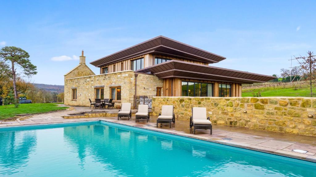 a house with a swimming pool in front of a house at Badgerwood in Winchcombe