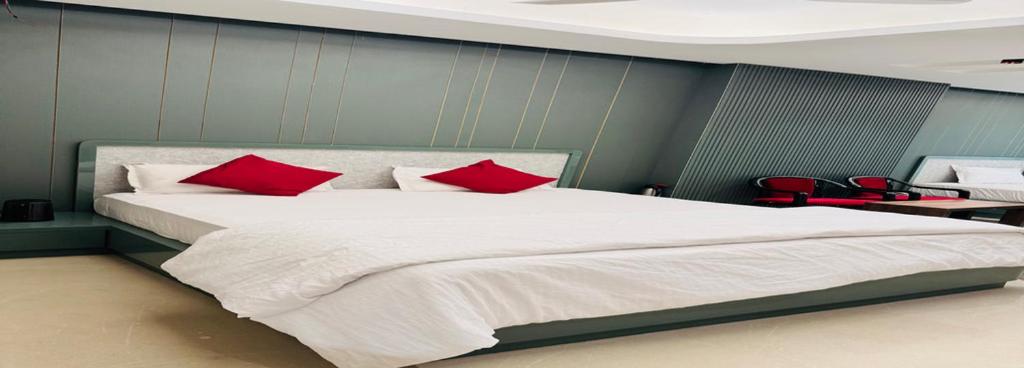 a bedroom with a large white bed with red pillows at Hotel Royal Plaza in Phulabāni