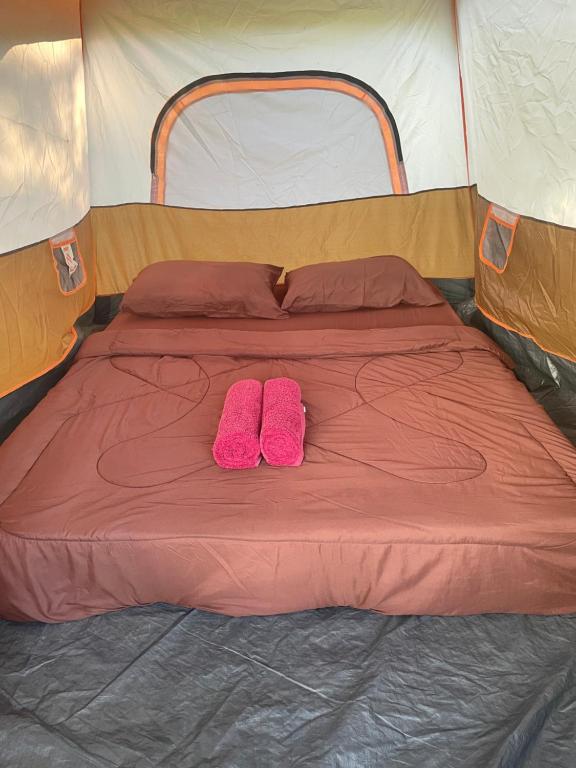 een paar roze schoenen die op een bed in een tent staan bij Kohkood camp in Ban Khlong Mat