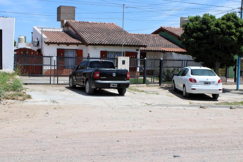 twee auto's geparkeerd voor een huis bij Clau Propiedades in San Antonio Oeste