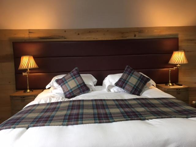 a bedroom with a bed with pillows and two lamps at Ravelston House in Musselburgh