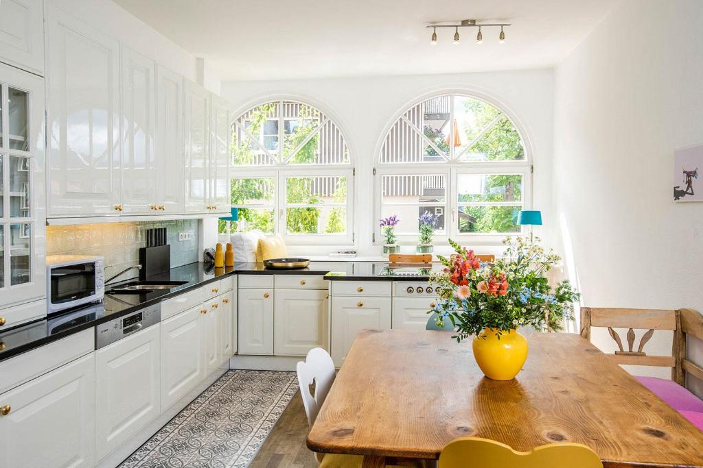 een keuken met een houten tafel en een vaas met bloemen bij Strömbergs Merle in Oberstaufen