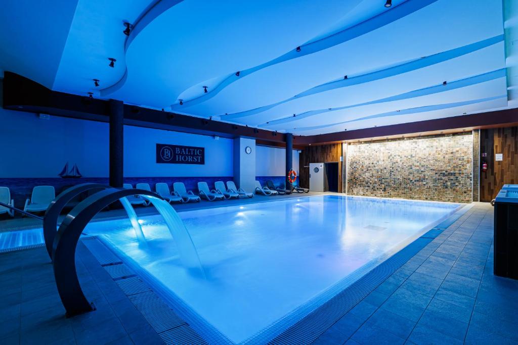 a large swimming pool in a building with blue lights at Apartamenty Baltic Horst Basen & Restauracja in Niechorze